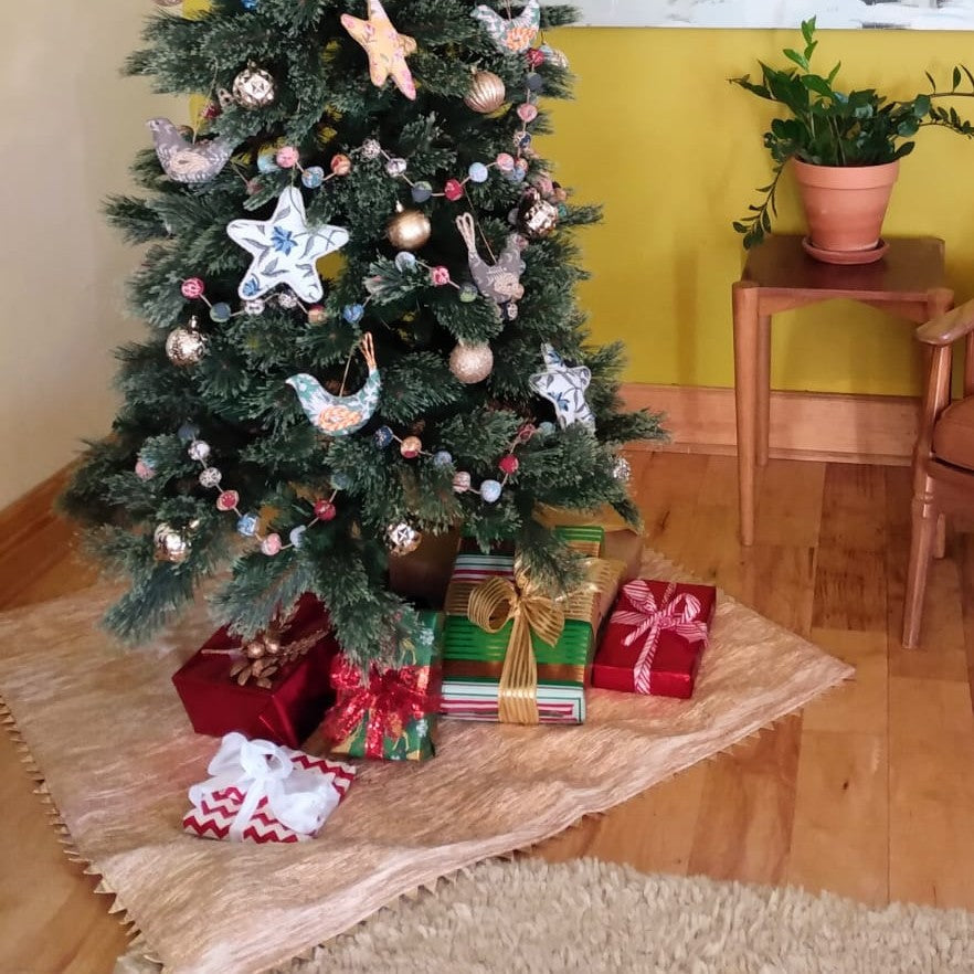 Square tree skirt made from upcycled golden-brown vintage saree fabric with woven texture and zigzag pinking shear edges, featuring a center opening with beige ribbon ties for closure, photographed against a white background