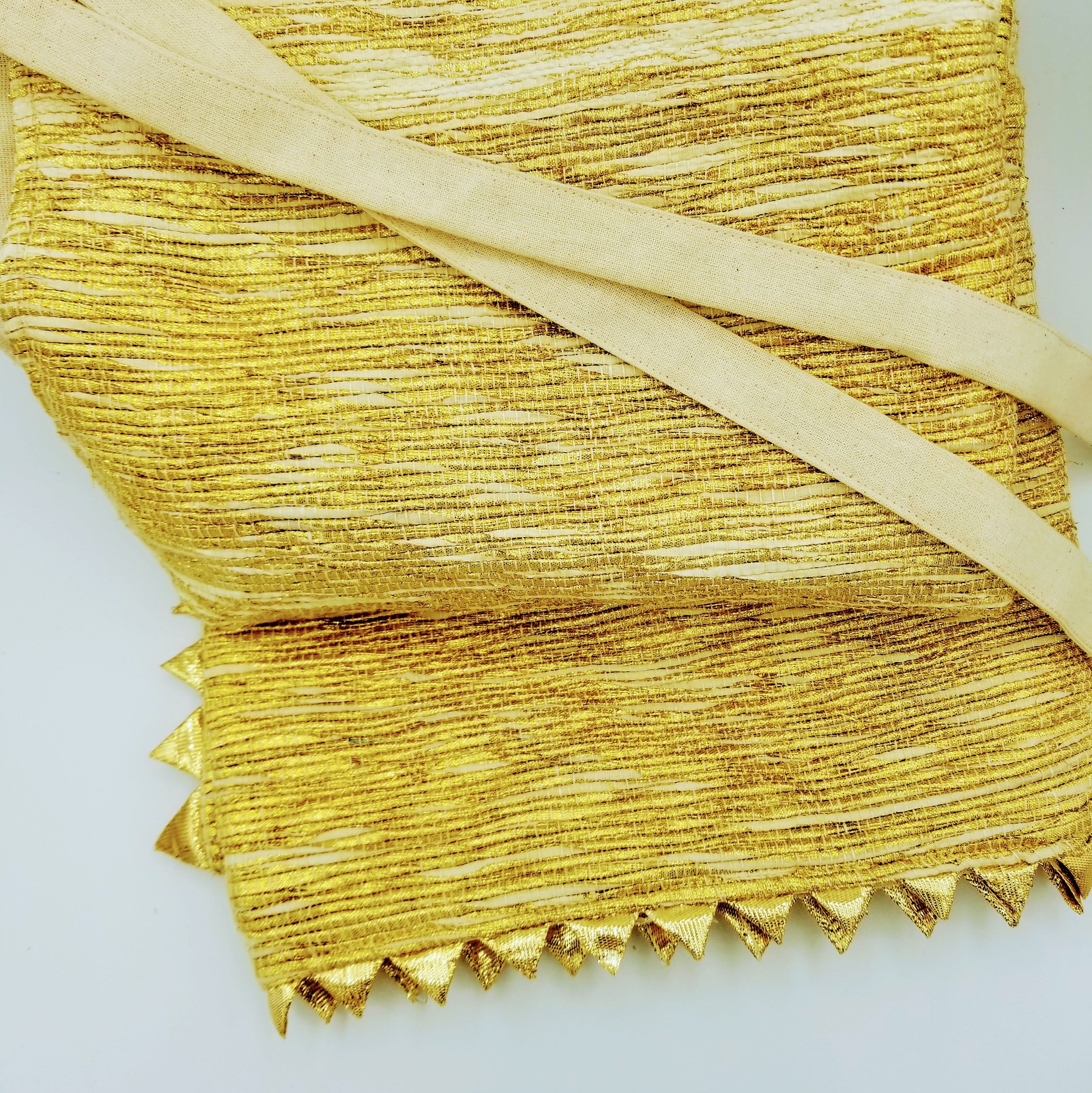 Square tree skirt made from upcycled golden-brown vintage saree fabric with woven texture and zigzag pinking shear edges, featuring a center opening with beige ribbon ties for closure, photographed against a white background