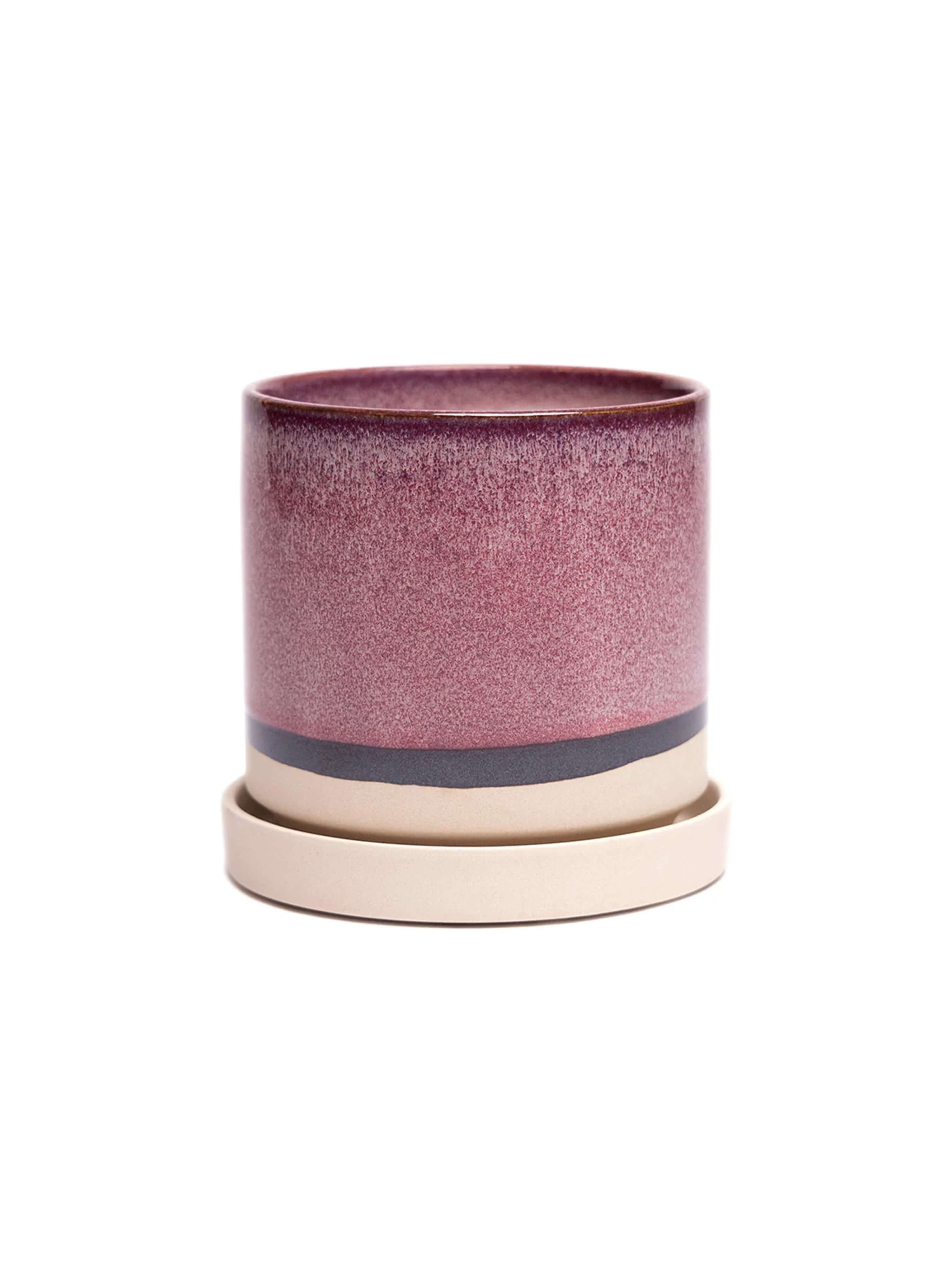 A handmade ceramic plant pot with matching saucer featuring pink and cream glazed finishes with dark accent bands, displayed against a white background