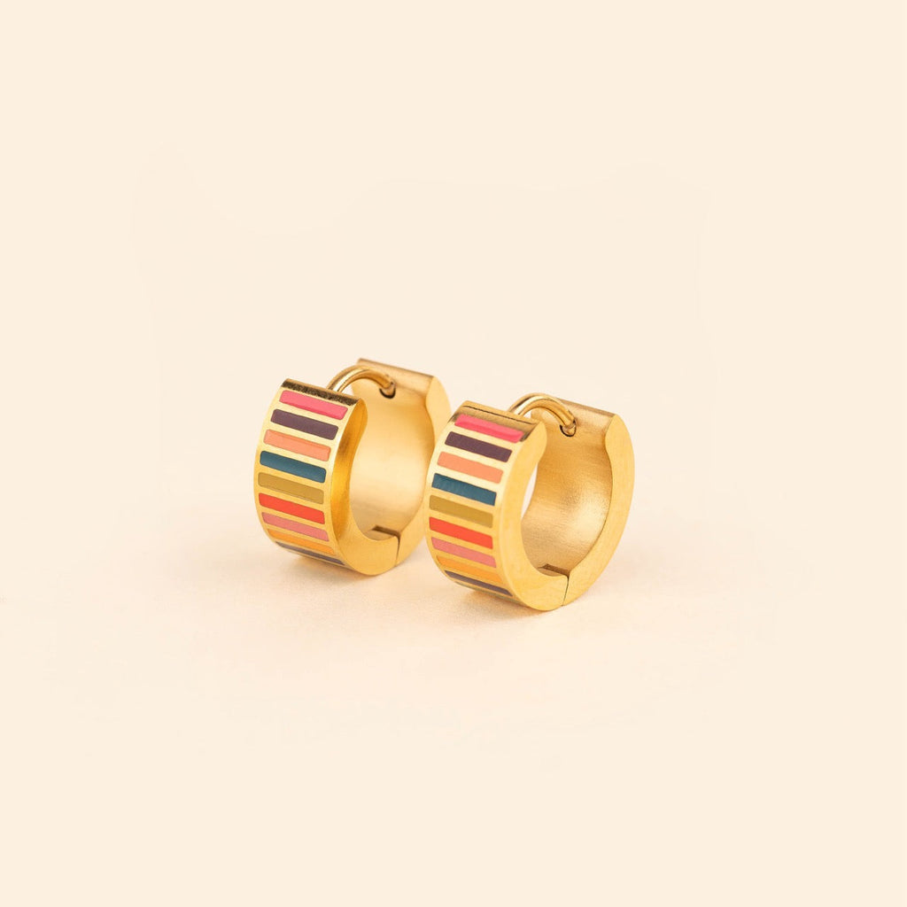 Pair of small gold-plated stainless steel hoop earrings with colorful horizontal stripes in pink, burgundy, orange, teal, and red enamel, photographed on a beige background