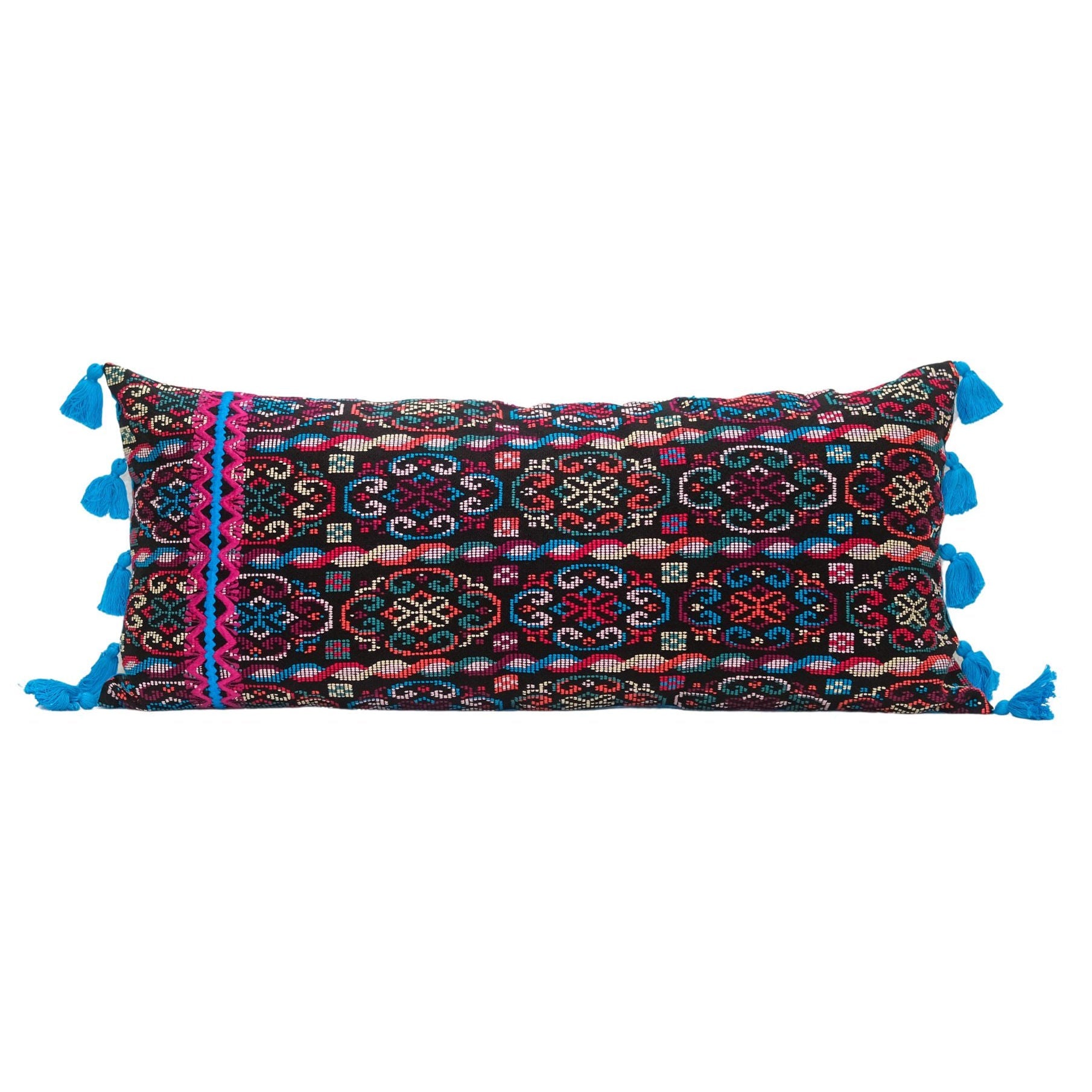 Hand woven lumbar pillow from Guatemala featuring intricate geometric patterns in vibrant colors including red, blue, pink, and white on a dark background, with bright blue tassel trim along both long edges, displayed against a white background