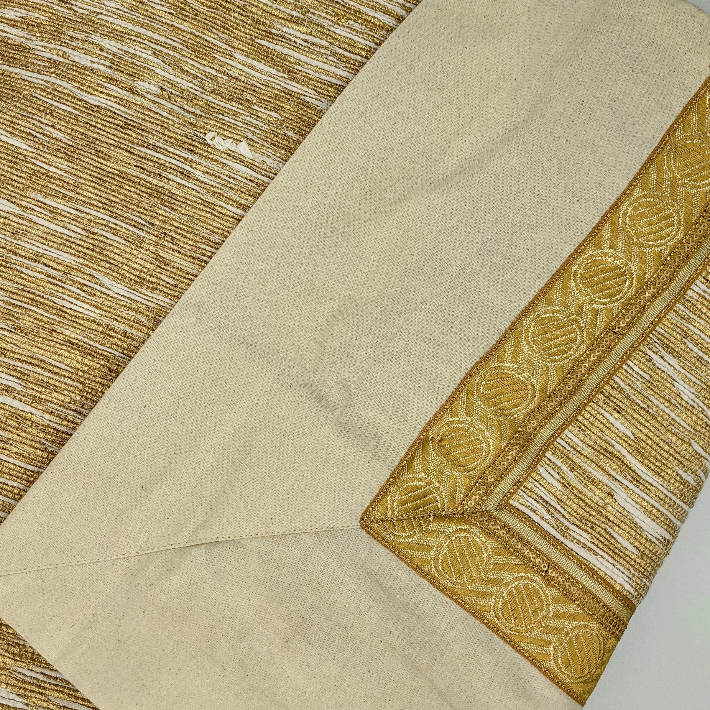 Circular tree skirt made from upcycled golden-brown vintage saree fabric with intricate woven texture and decorative border trim, featuring a center opening with white ribbon ties, photographed on a neutral background