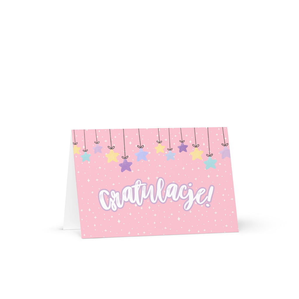 Polish greeting card with pink background featuring "Gratulacje!" text in white script lettering, decorated with hanging colorful stars and small sparkle details throughout