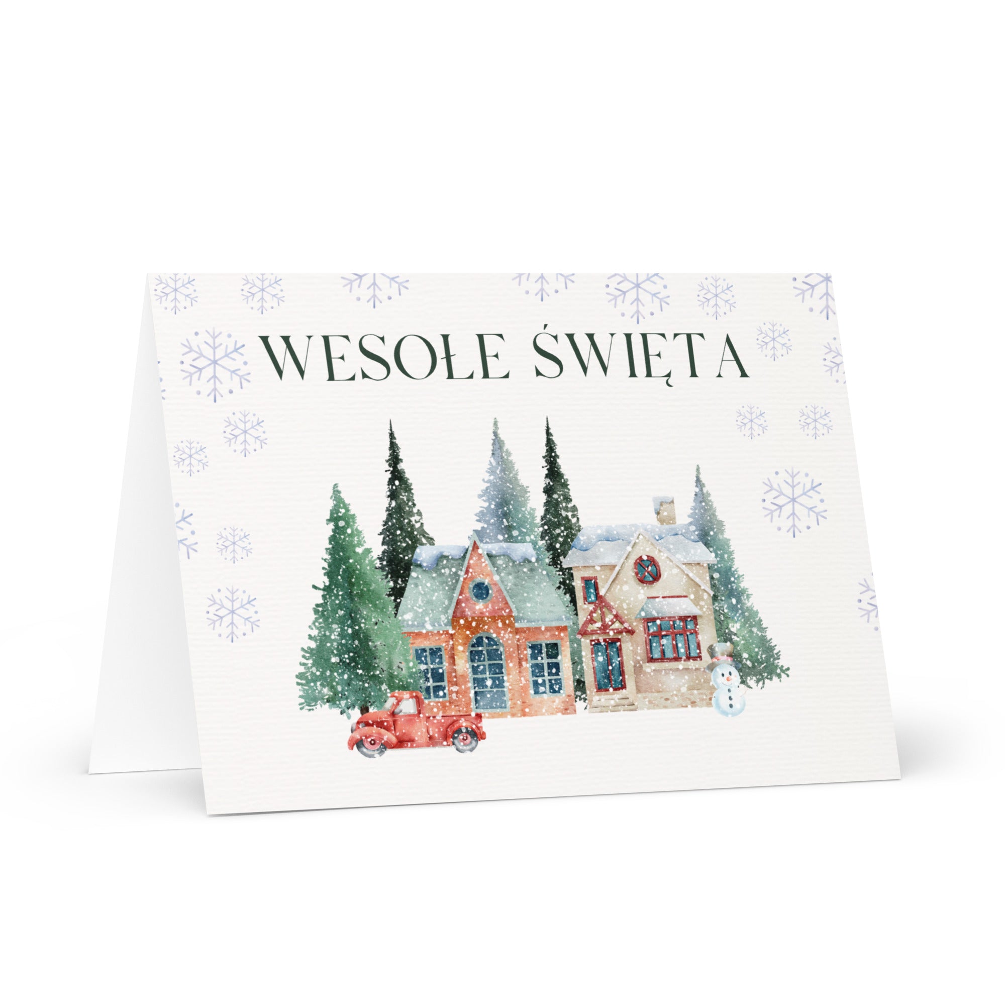 Polish Christmas greeting card featuring "Wesołe Święta" text with watercolor illustration of snowy village scene with cottages, pine trees, snowman, and vintage truck surrounded by delicate snowflake pattern, displayed with white envelope