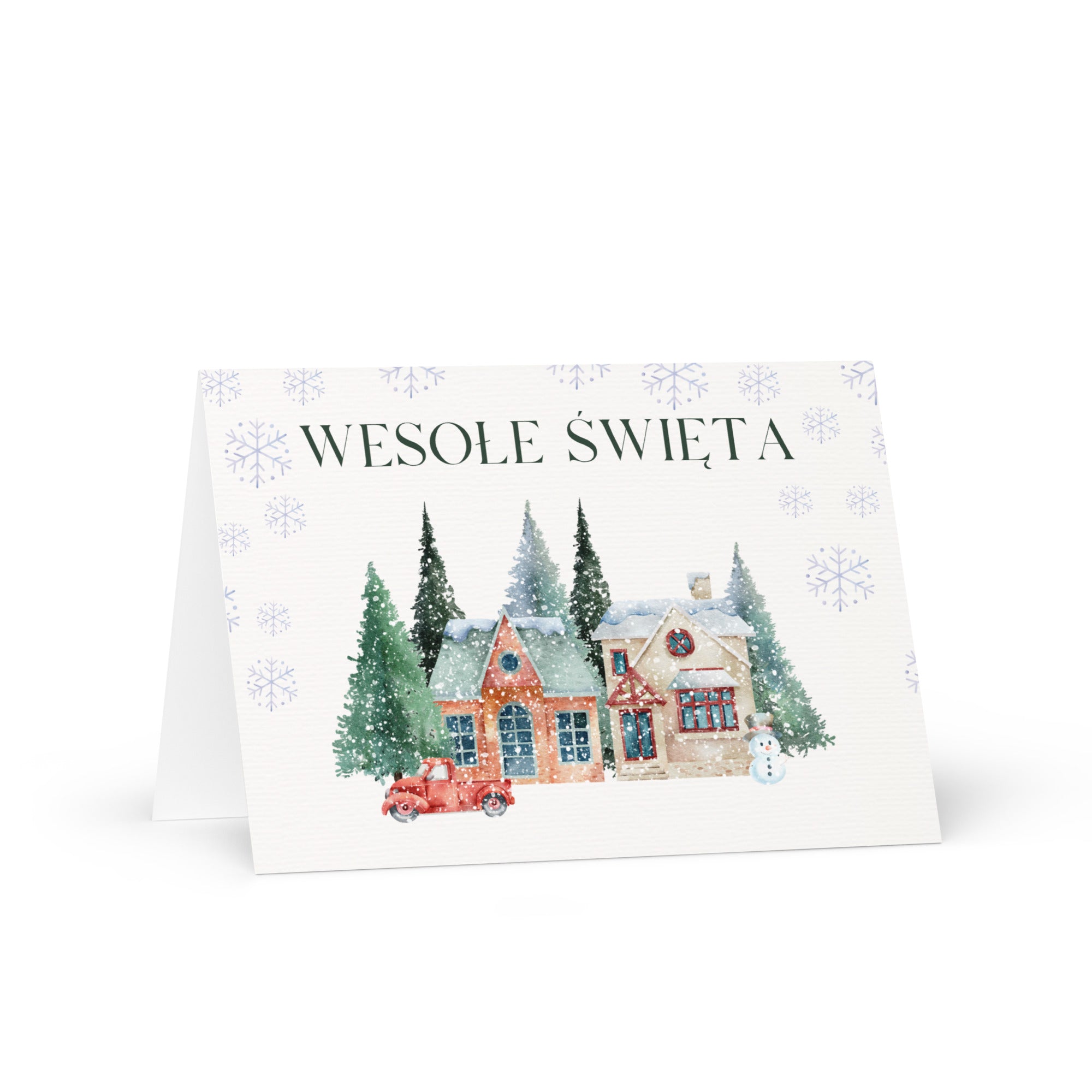 Polish Christmas greeting card featuring "Wesołe Święta" text with watercolor illustration of snowy village scene with cottages, pine trees, snowman, and vintage truck surrounded by delicate snowflake pattern, displayed with white envelope