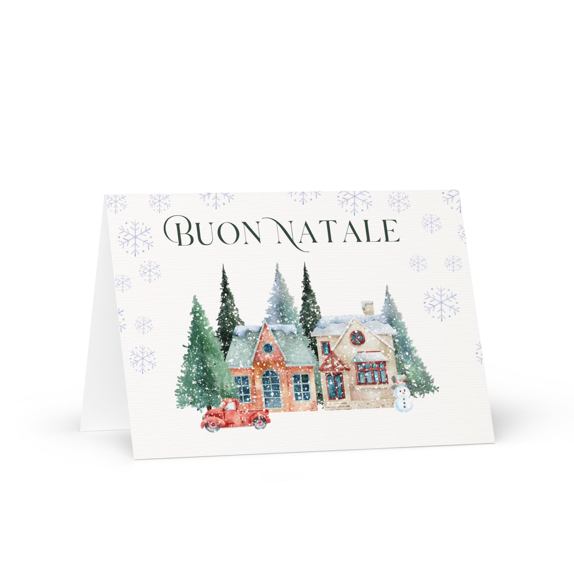 Italian Christmas greeting card featuring "Buon Natale" text with watercolor illustration of snowy village scene with cottages, pine trees, snowman, and vintage truck surrounded by delicate snowflake pattern