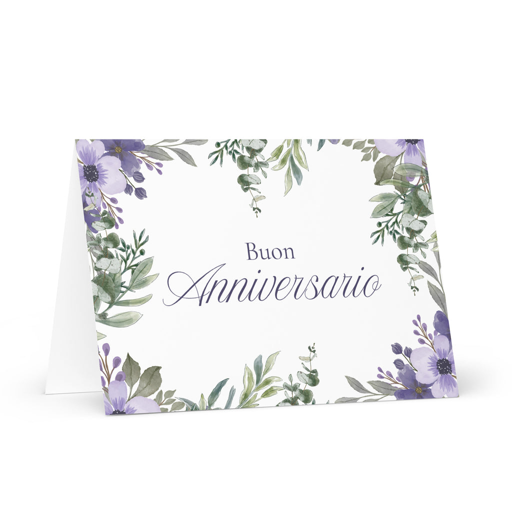 Italian anniversary greeting card featuring "Buon Anniversario" text in elegant script on white background, decorated with watercolor purple flowers and green botanical leaves in corner arrangement