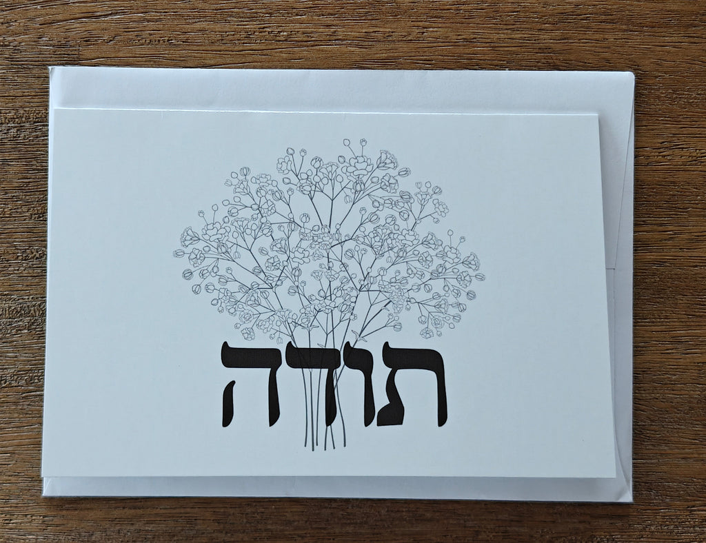 White card with black floral design and text on a wooden surface