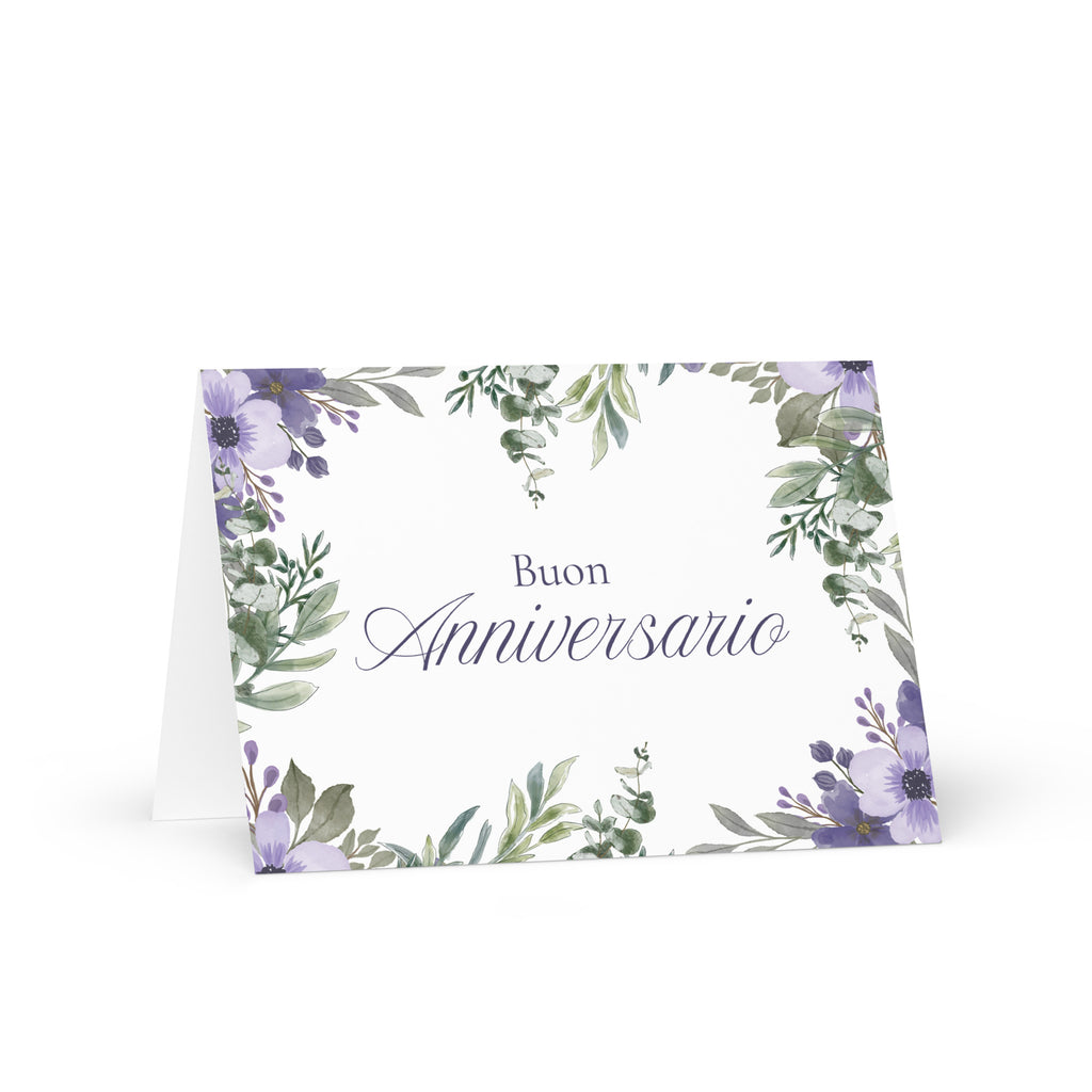 Italian anniversary greeting card featuring "Buon Anniversario" text in elegant script on white background, decorated with watercolor purple flowers and green botanical leaves in corner arrangement
