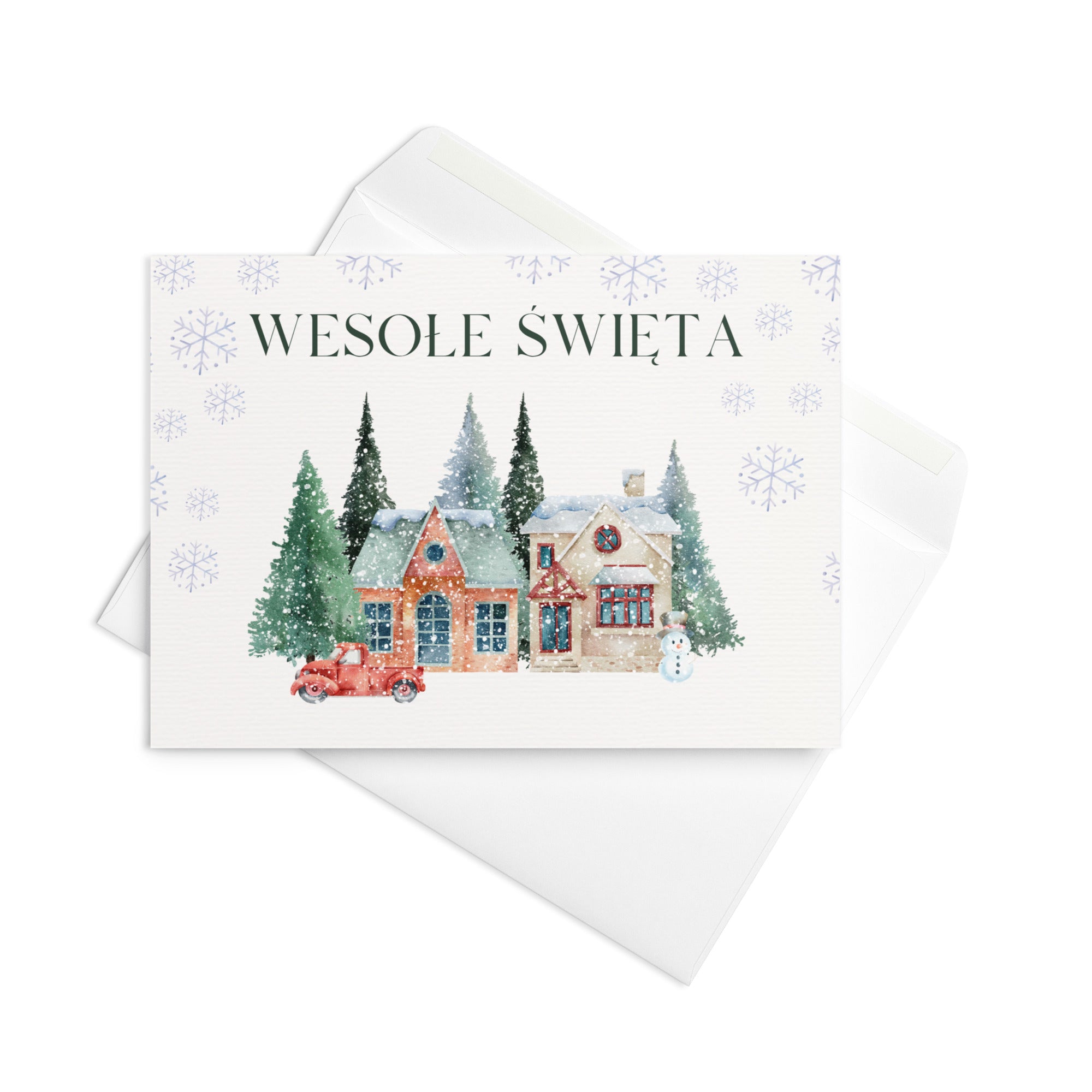 Polish Christmas greeting card featuring "Wesołe Święta" text with watercolor illustration of snowy village scene with cottages, pine trees, snowman, and vintage truck surrounded by delicate snowflake pattern, displayed with white envelope