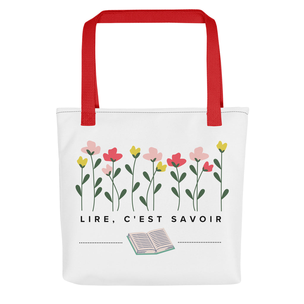 White canvas tote bag with red handles featuring hand-drawn pink, coral, and yellow flowers with green stems at top, French text "LIRE, C'EST SAVOIR" (to read is to know) in center, and small open book illustration at bottom