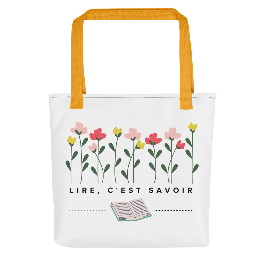 White canvas tote bag with yellow handles featuring hand-drawn pink, coral, and yellow flowers with green stems at top, French text "LIRE, C'EST SAVOIR" (to read is to know) in center, and small open book illustration at bottom