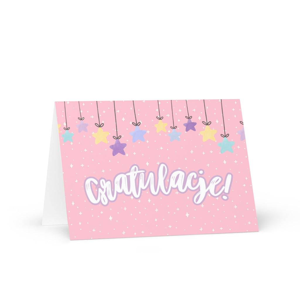 Polish greeting card with pink background featuring "Gratulacje!" text in white script lettering, decorated with hanging colorful stars and small sparkle details throughout