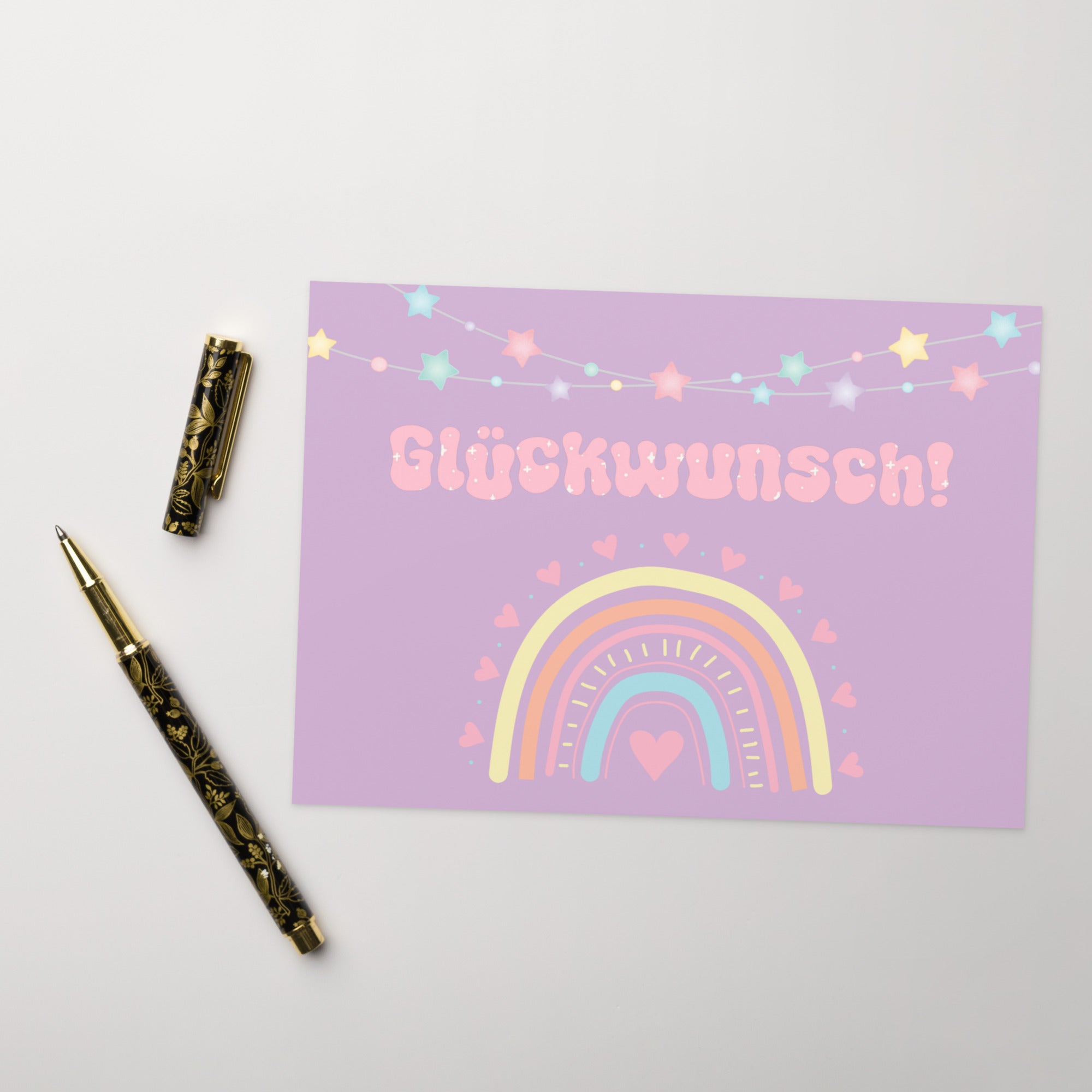 German greeting card with purple background featuring "Glückwunsch!" text in pink bubble letters, decorated with a pastel rainbow, colorful star garland, and small heart details