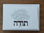 White card with black floral design and text on a wooden surface