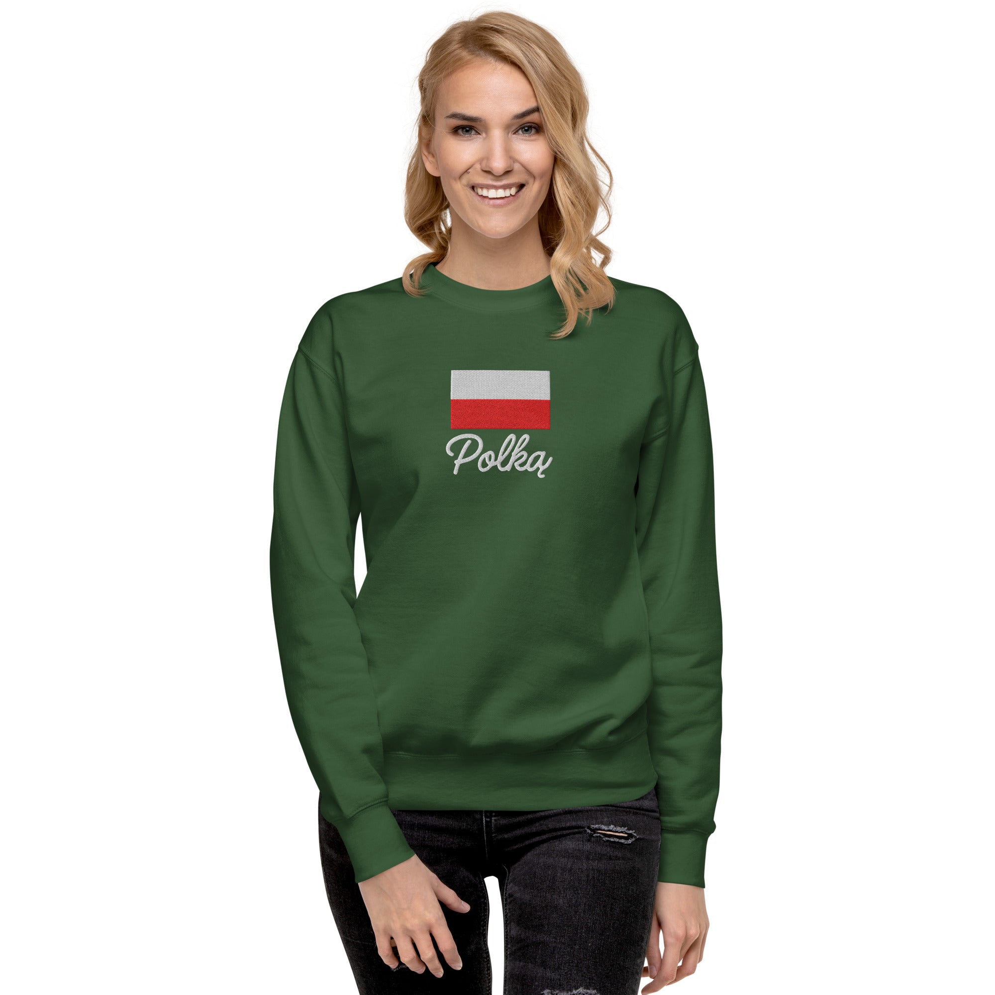 Green crew neck sweatshirt modeled on person, featuring embroidered Polish flag in white and red colors above white embroidered text "Polka" in script font