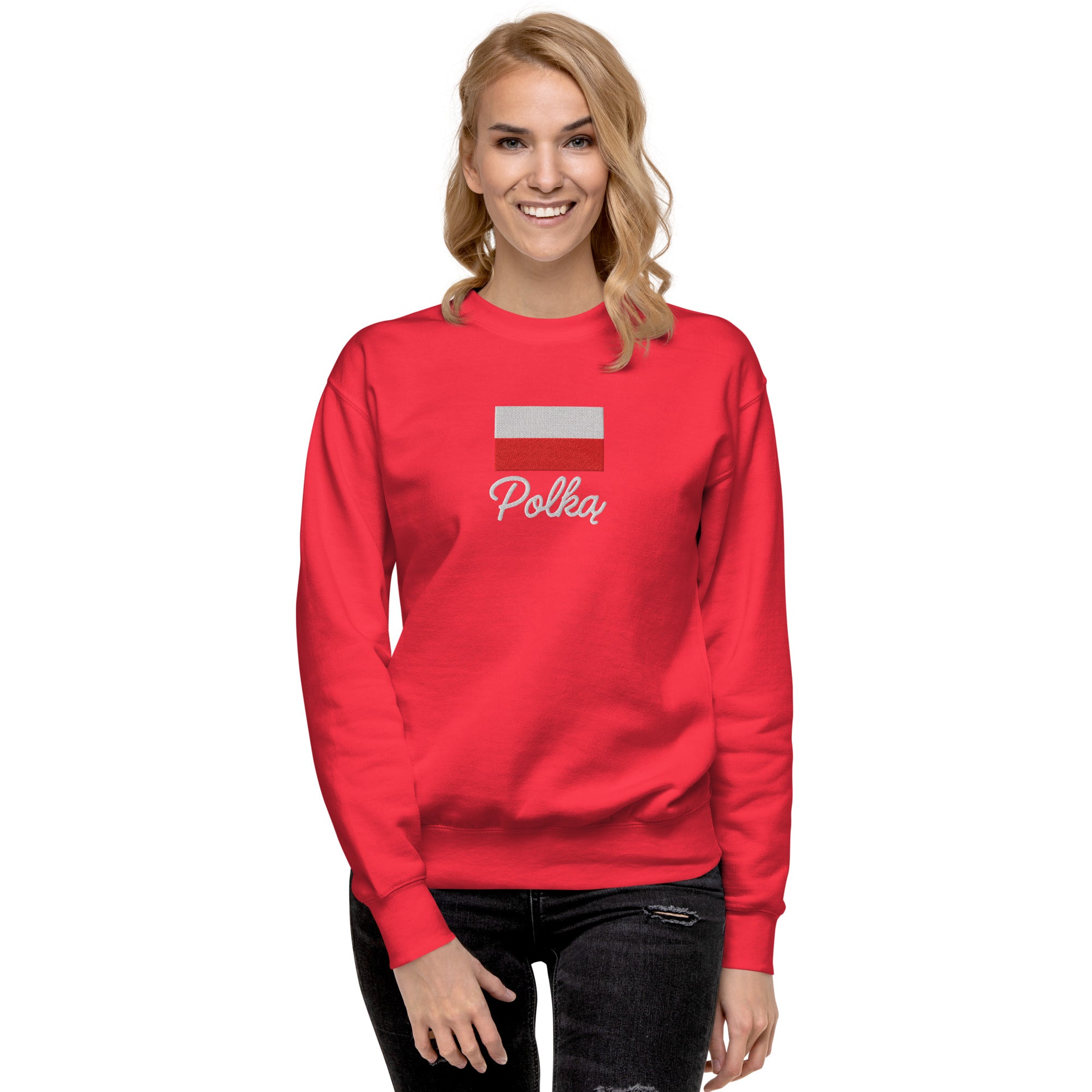 Red crew neck sweatshirt modeled on person, featuring embroidered Polish flag in white and red colors above white embroidered text "Polka" in script font